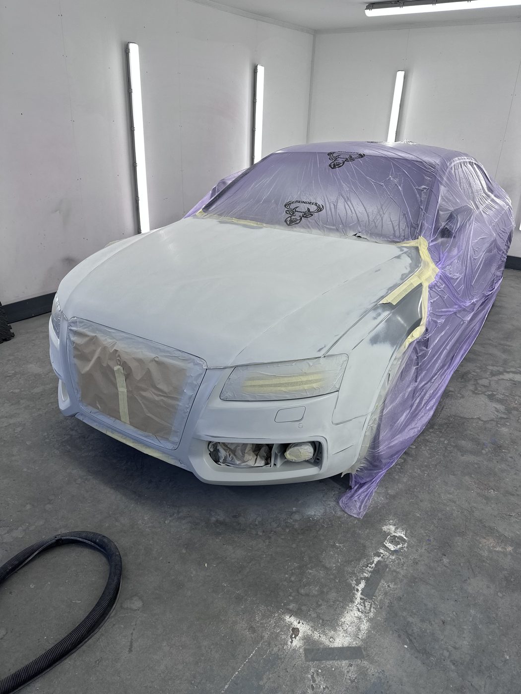 Audi in primer, masked up mid-respray in the paint booth